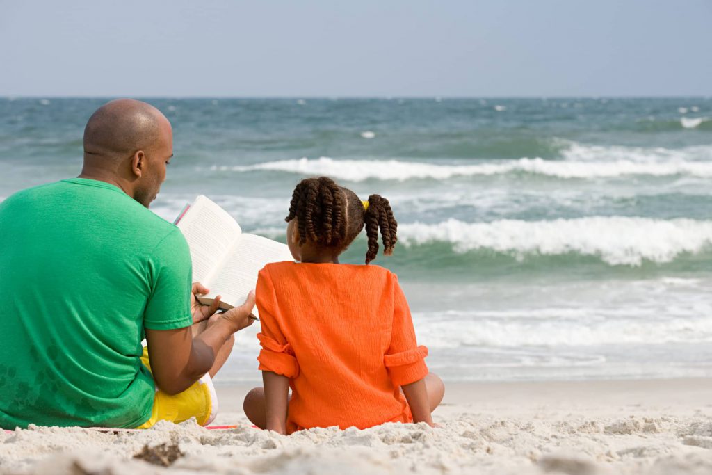 Father and Daughter reading on the beach in the Outer Banks.