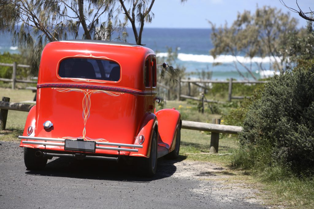 Red hot rod parked at a beach access overlooking the atlantic ocean.