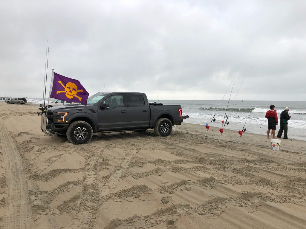 truck on beach with surf fishermen