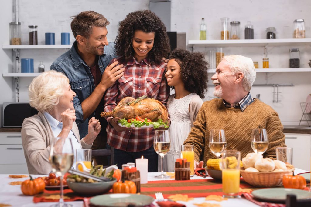 A family gathering and admiring a perfectly cooked turkey around the dinner table during Thanksgiving