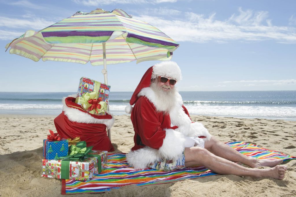 Santa sitting on the beach under an umbrella