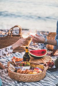 A picnic dinner on the beach complete fresh watermelon, cheese, bread and wine