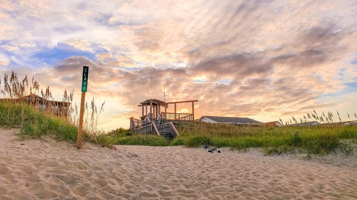 a gazebo on the beach facing the sunset