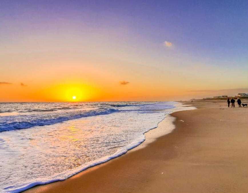 Sunset over the ocean with waves along the shore in the Outer Banks.
